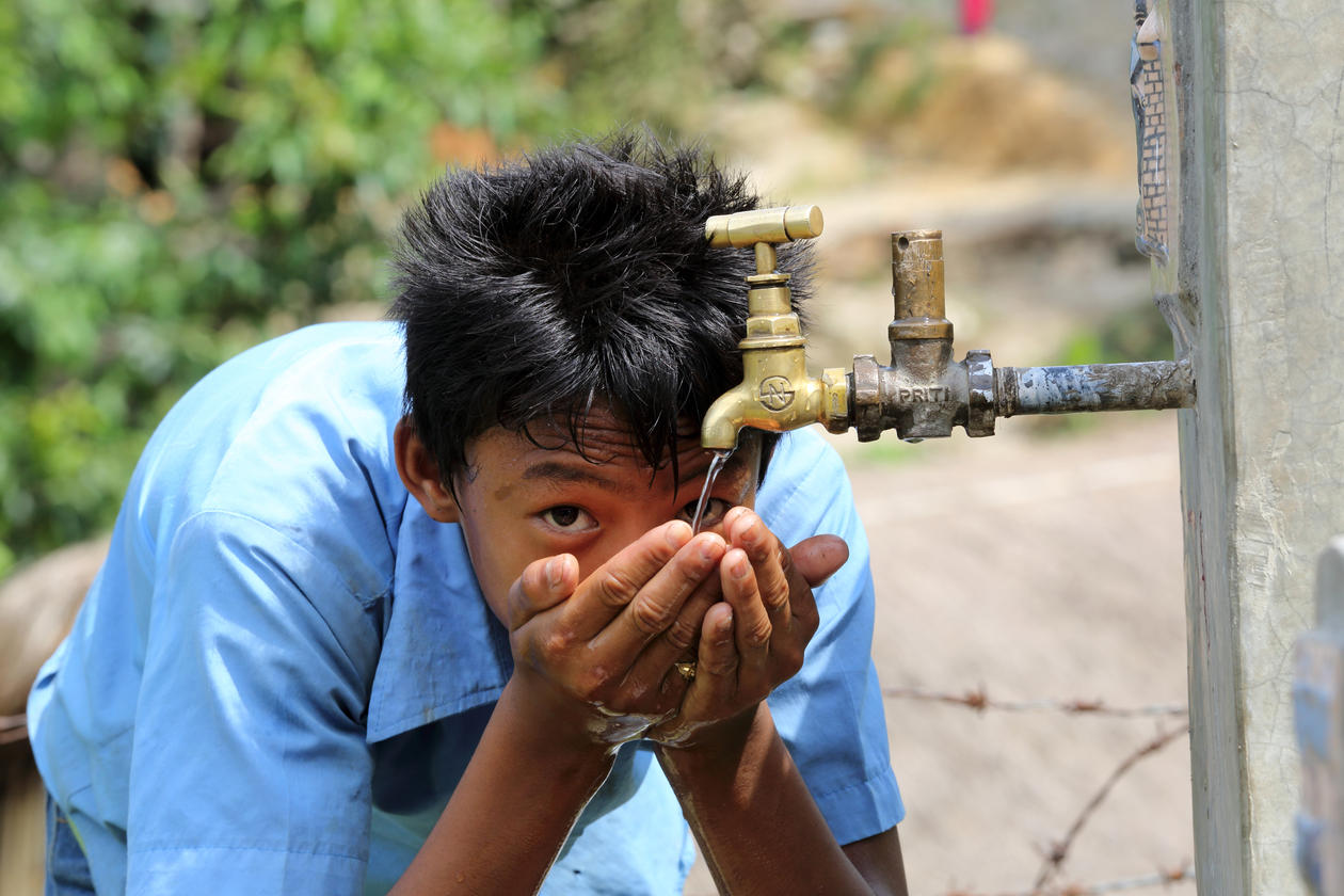 Boy drinks water from a tap stand at the school, NEWAH WASH water project in Puware Shikhar, Udayapur District, Nepal.