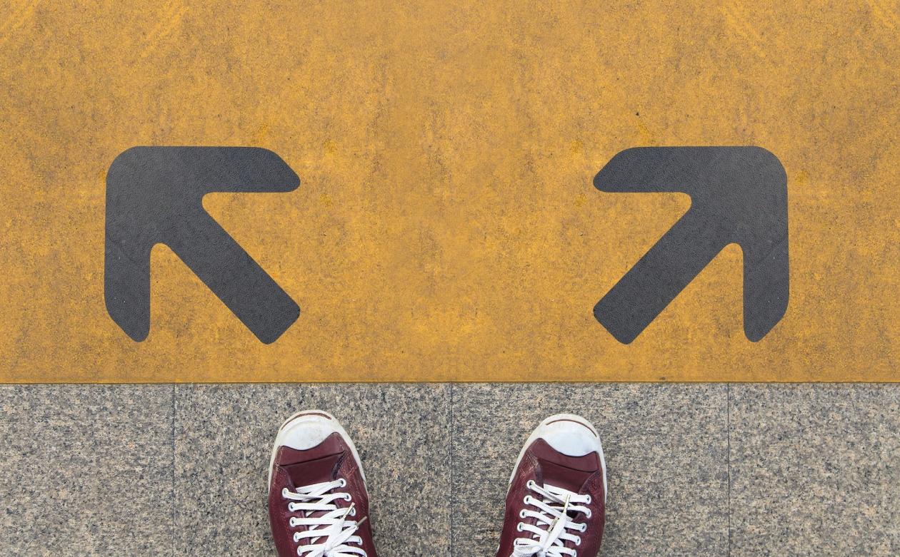 A photo of two shoes in front of to arrows going in different directions