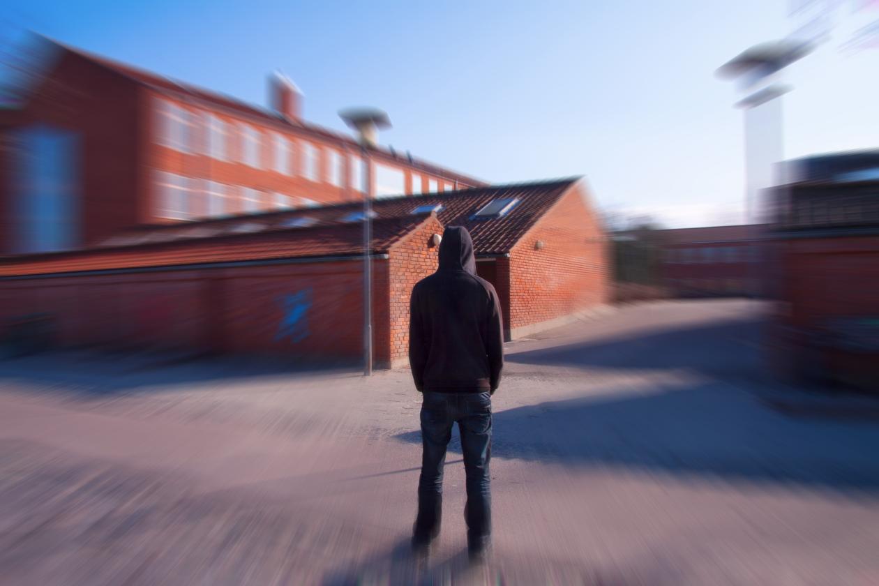 Teenager boy in black hoodie standing outside school