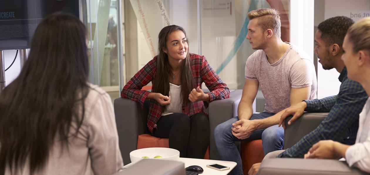 Fem studenter diskuterer sittende i en sofa