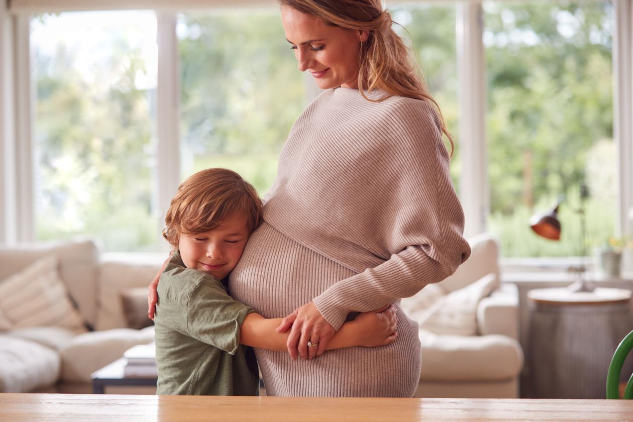 Illustrasjonsfoto av en gravid dame som får en klem av et barn. 