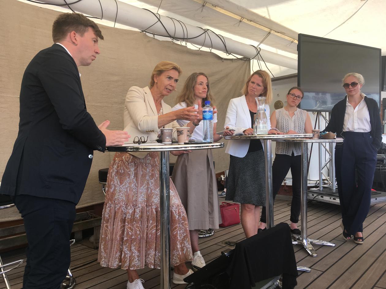 A passionate Kristin H. Holth speaking during a debate in Arendal, Norway on 14 August 2019  whilst (left to right) Inga Berre, Hege Økland, Ragnhild Freng Dale, and Hege Hammersland-White listen. Moderator Ole Øvretveit on far left. 