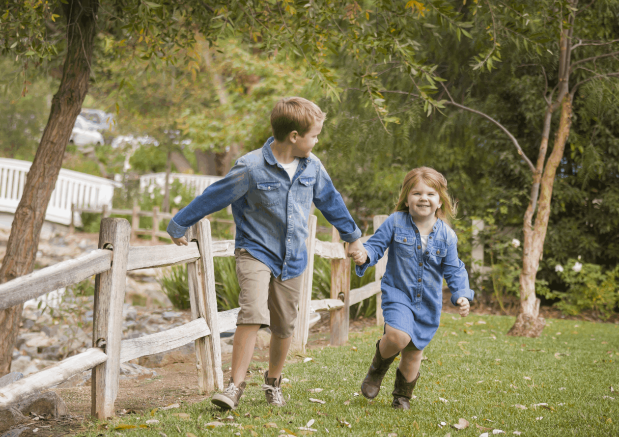 Happy Young Brother and Sister Running Together Outside.