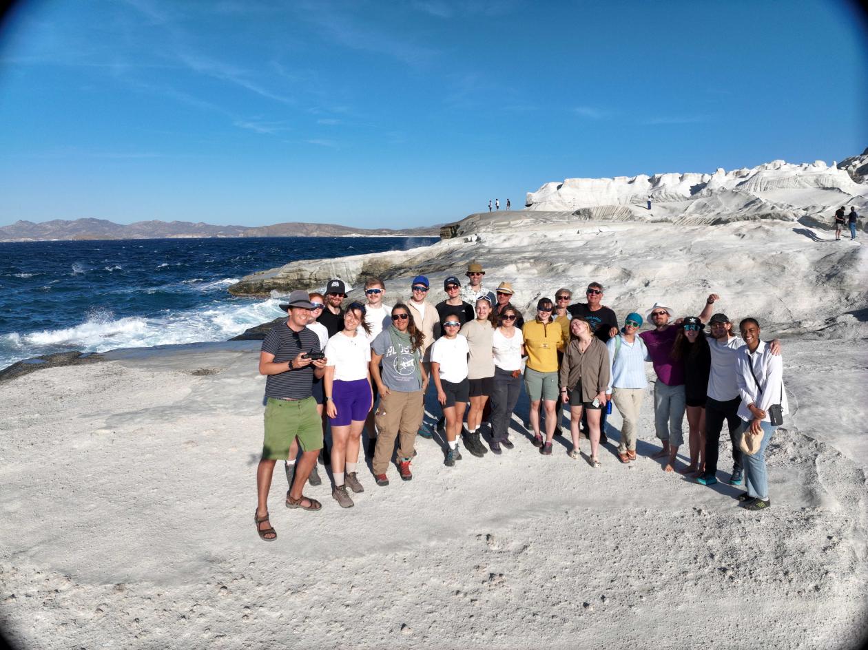 group of students standing on a beach in front of white rock cliffs