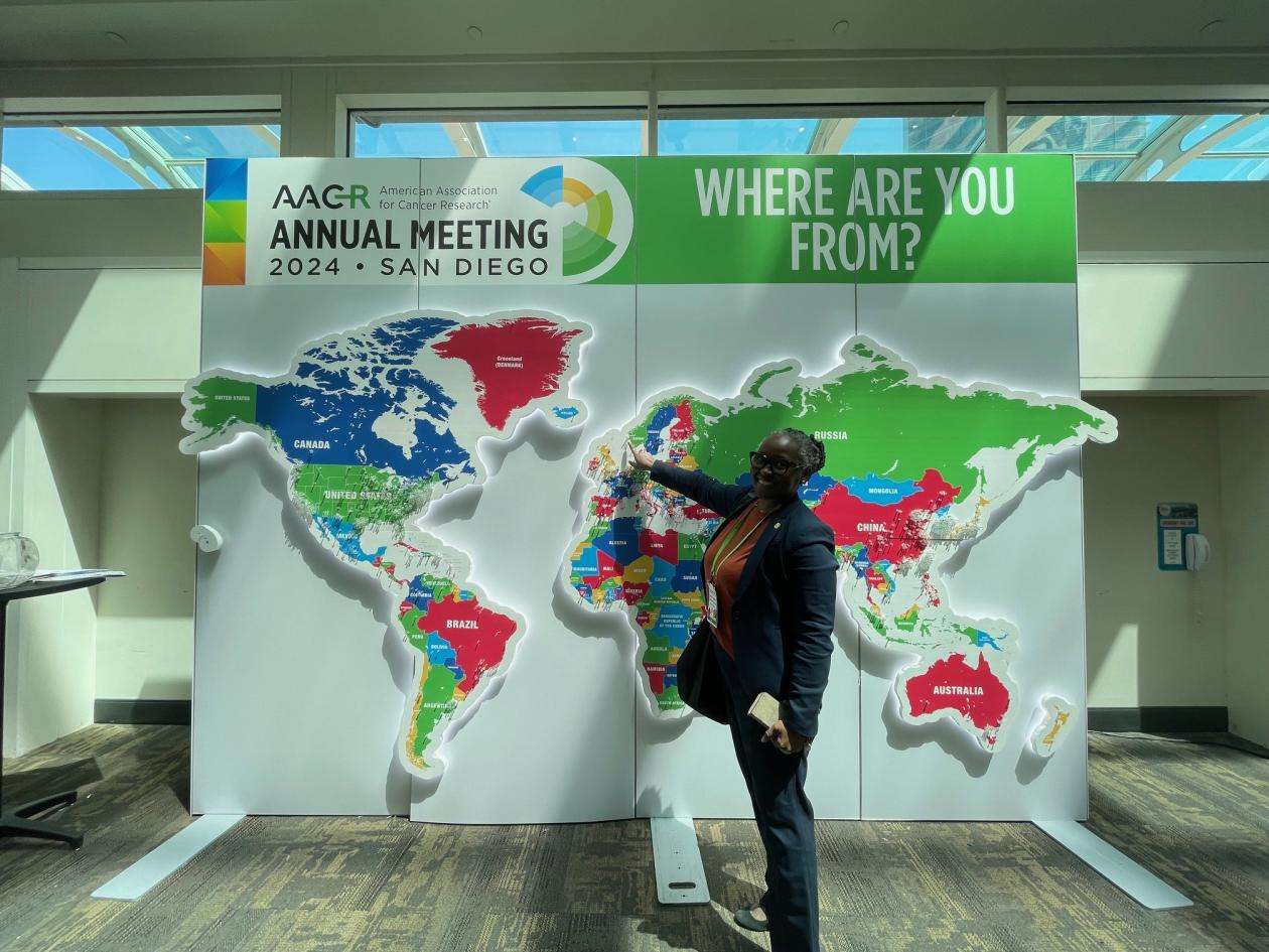 Martha Enger pointing at Bergen, Norway on a big world map showing where the participants to the conference are from