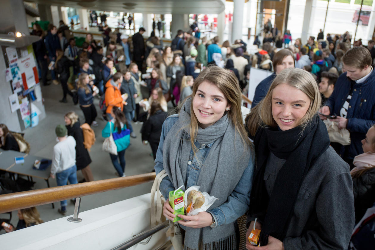 To jenter står i forgrunnen i trappen på Studentsenteret, bak ser du mange elever, en stor folkemengde