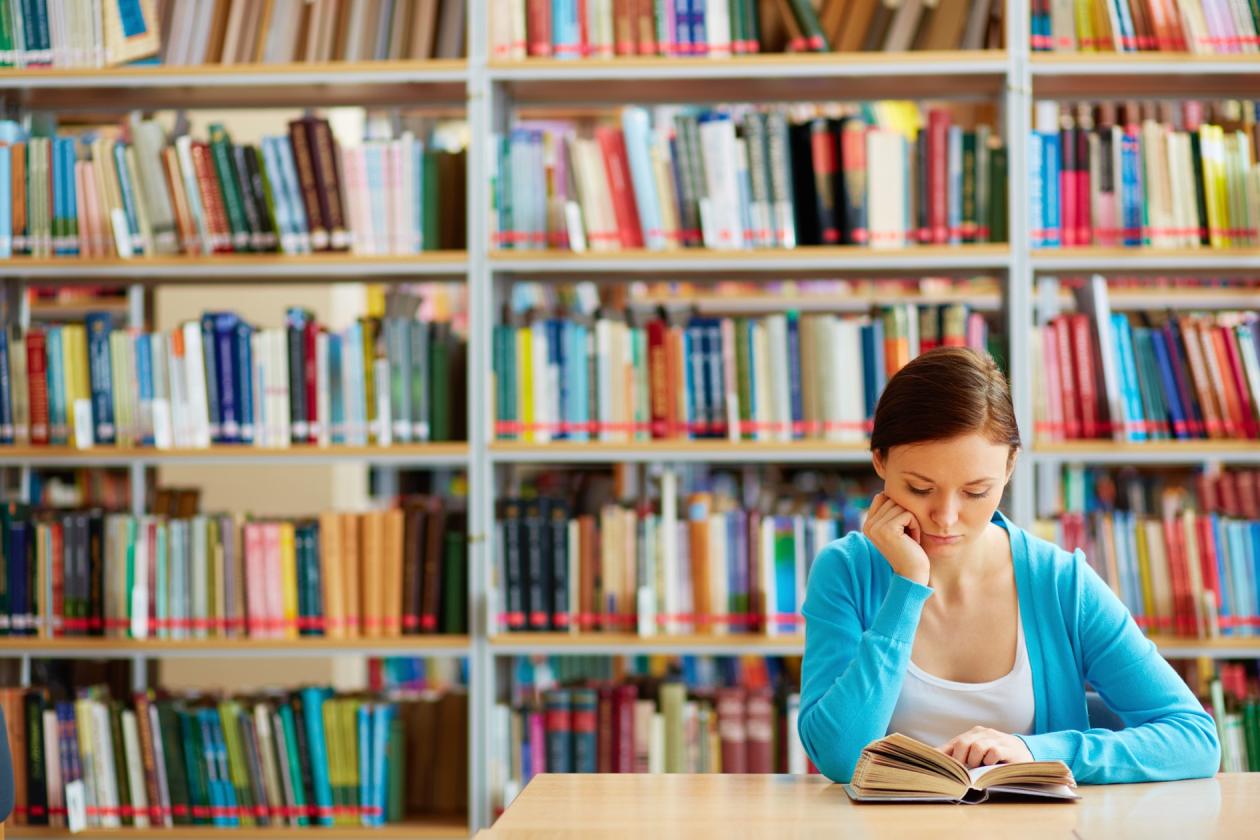 En student som leser en bok i et bibliotek