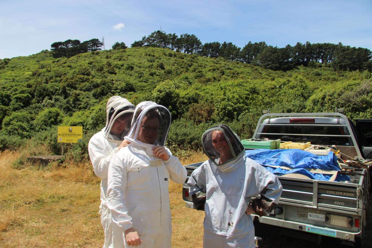 Three beekeepers suiting up in protective gear