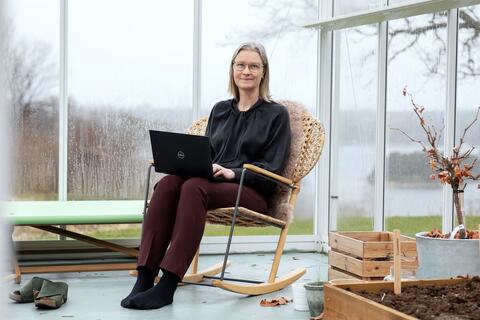 Kirsti Nordstrand sit i gyngestol med laptop og arbeider