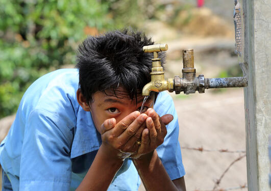 Boy drinks water from a tap stand at the school, NEWAH WASH water project in Puware Shikhar, Udayapur District, Nepal.
