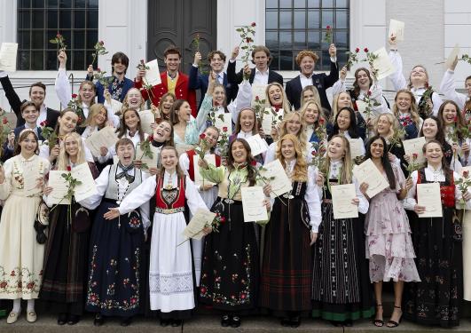 Studenter på avslutningsseremoni med diplom og roser i hendene