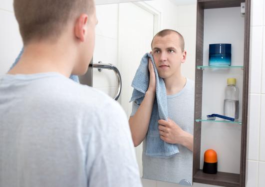 Illustrasjonsbilde av ung mann på badet som ser seg i speilet