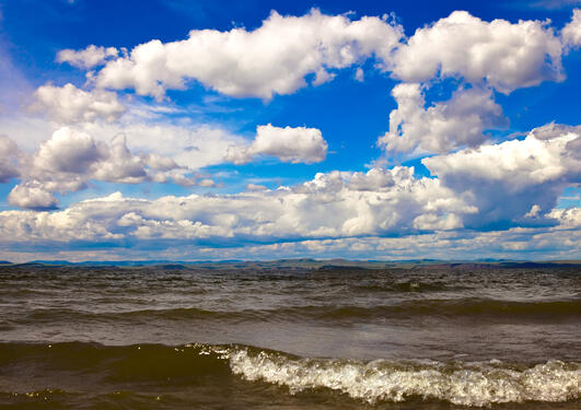 Photo of the ocean with a blue sky with light clouds.