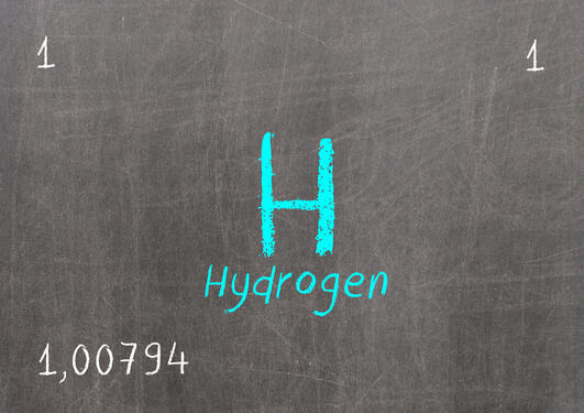 Image of the chemical symbol H representing hydrogen written with white chalk on a green blackboardk on