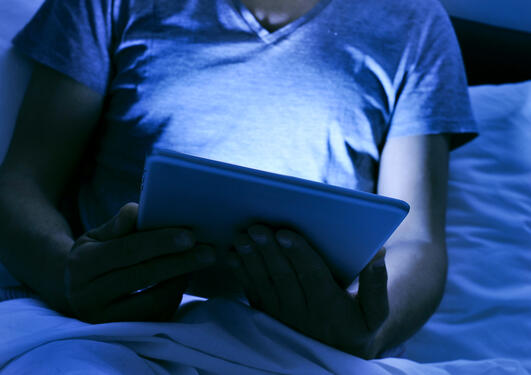 Nærbilde av mann som leser netbrett på sengen