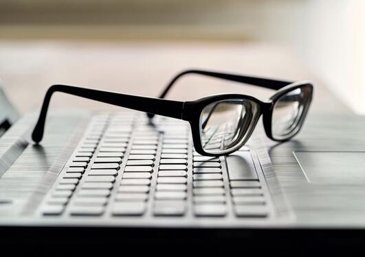 The picture shows  glasses and computer keyboard