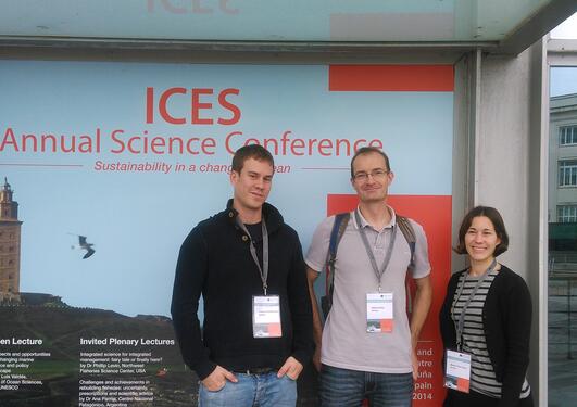 Fabian, Mikko and Bea posing in front of the conference poster