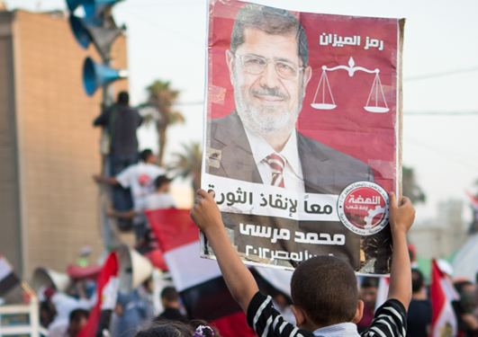 Ein gut held opp ein plakat av Muhammad Morsi, Egypts tidlegare president.