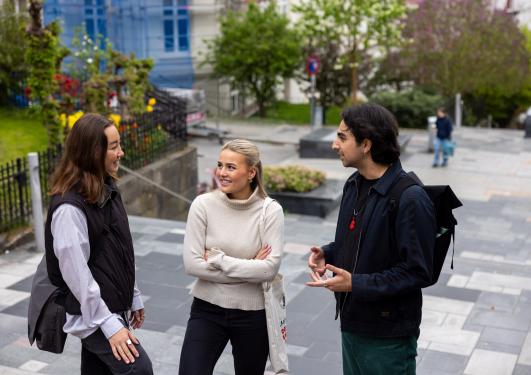 Tre studenter som snakker sammen med Bergen i bakgrunnen