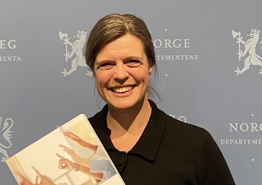 Photo of Ingrid Miljeteig holding her report
