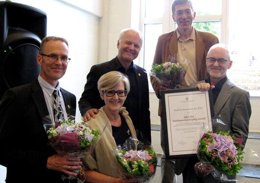 De fire mottakerne av Studiekvalitetsprisen og dekanen smiler mot kamera med blomster og diplom