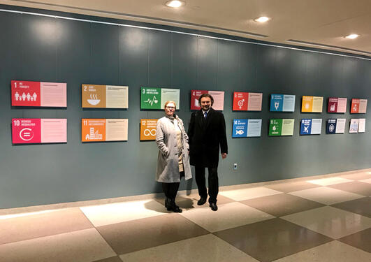 UiB's Vice-Rector for Global Relations Annelin Eriksen and Professor Edvard Hviding in front of the symbols for the 17 Sustainable Development Goals in the United Nations building in New York.