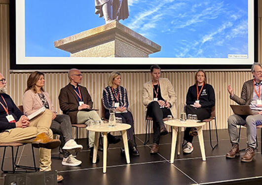 Sju paneldeltakere sitter på en scene under en paneldebatt på UiB.