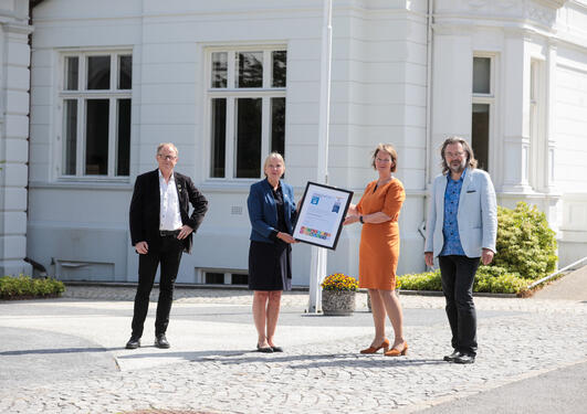 Rector Margareth Hagen is handed a UN certificate from Lise Øvreås of SDG Bergen Ocean for the University of Bergen becoming UNAI SDG14 Hub 2021-2024 with Marine Director Amund Maage (left)  and Edvard Hvidingi of SDG Bergen Science Advice (right).