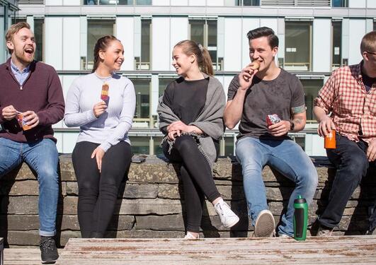 Studenter i Bergen som hygger seg med is i solskinnet.